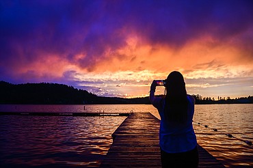 Madison McLean photographs the sunset after a passing storm at Foys Lake on Saturday, July 2. (Casey Kreider/Daily Inter Lake)