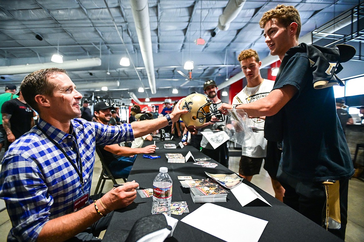 Former NFL quarterback and Super Bowl XLIV MVP Drew Brees autographs a New Orleans Saints helmet for brothers Robert and Jackson Walker, of Kalispell, at the World Gym Cares Fair on Wednesday, Aug. 10. (Casey Kreider/Daily Inter Lake)