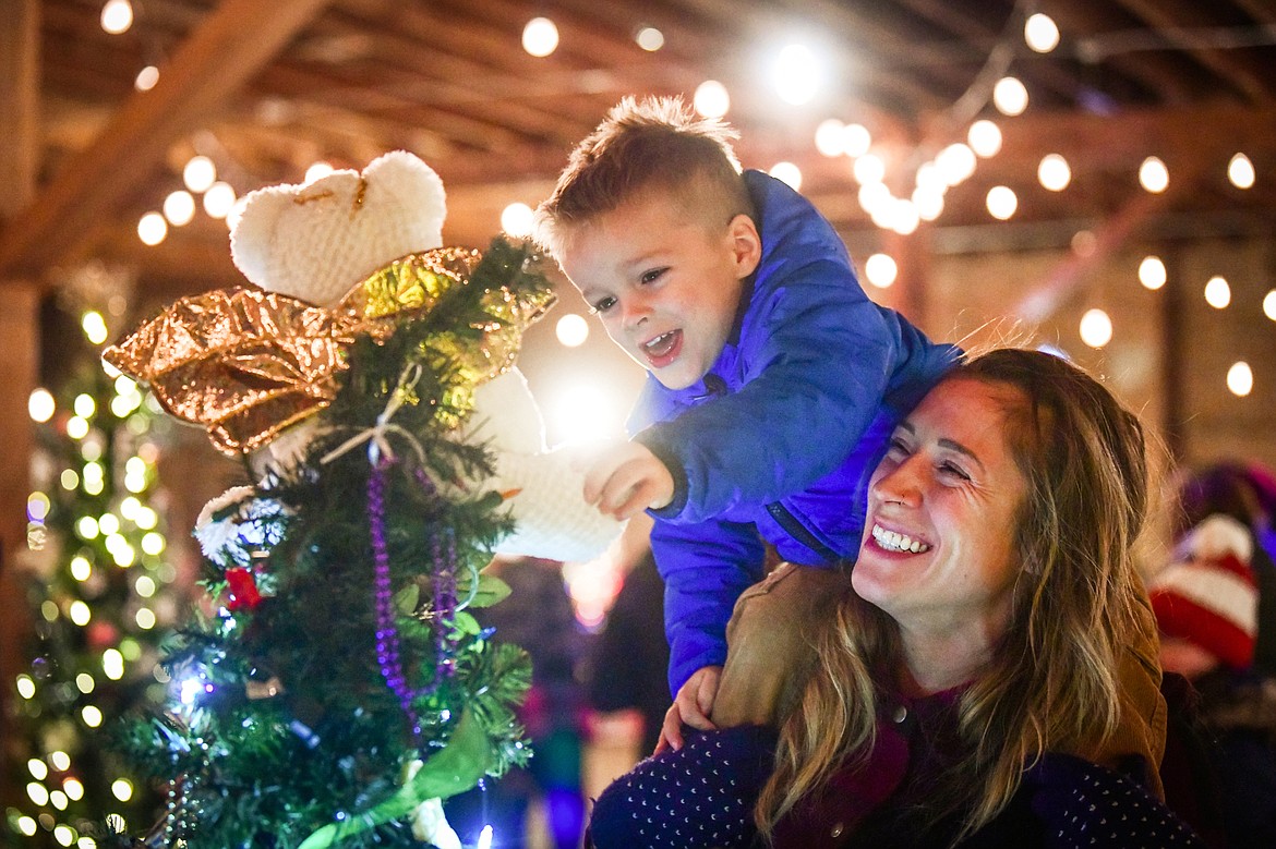 Jessica Pedersen and her son Kal check out the decorated Christmas trees at Mann Mortgage's Christmas Tree Extravaganza on the second floor of the KM Building during the Downtown Kalispell Holiday Stroll & Tree Lighting on Friday, Dec. 2. (Casey Kreider/Daily Inter Lake)