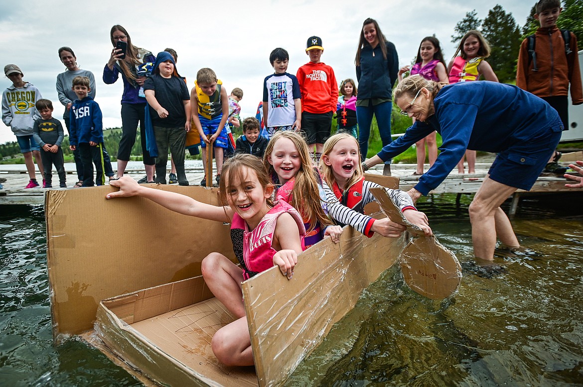 St. Matthew's School second-grader Felicity McCubbins, front, third-grader Brooklyn Houk, middle, and third-grader Addie Robbins, back, launch their homemade cardboard boat into Foy's Lake with the help of teacher Susie Rainwater on Friday, June 10. As part of St. Matthew's Jump Into Summer Science Program hosted by teacher Susie Rainwater, 47 students in grades 1-5 used applied science and math concepts to construct their crafts and test their buoyancy in the waters of Foy's Lake. (Casey Kreider/Daily Inter Lake)