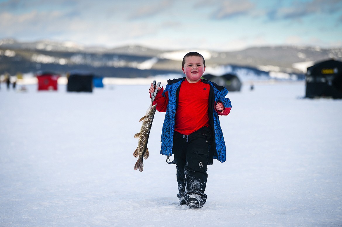 Aiden Jensen, from Kalispell, carries a pike to shore to be weighed at the 50th Sunriser Lions Family Ice Fishing Derby at Smith Lake in Kila on Saturday, Jan. 8. (Casey Kreider/Daily Inter Lake)