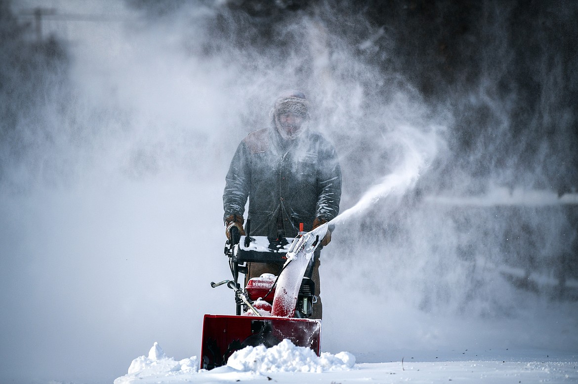Patrick Williams battles the wind as he clears snow in front of his residence along East Center Street on Wednesday, Dec. 21. (Casey Kreider/Daily Inter Lake)