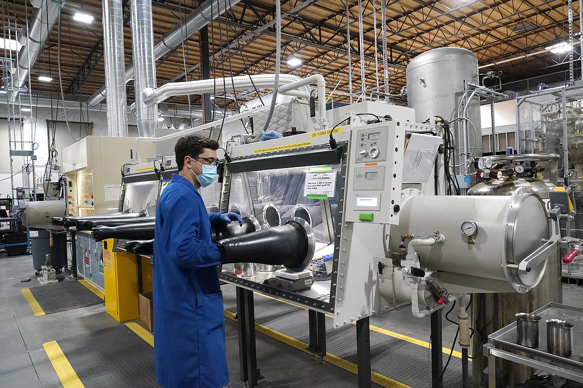 Test engineer Jacob Wilcox pulls his arm out of a glove box used for processing sodium at TerraPower, a company developing and building small nuclear reactors, Jan. 13, 2022, in Everett, Wash. (AP Photo/Elaine Thompson, File)