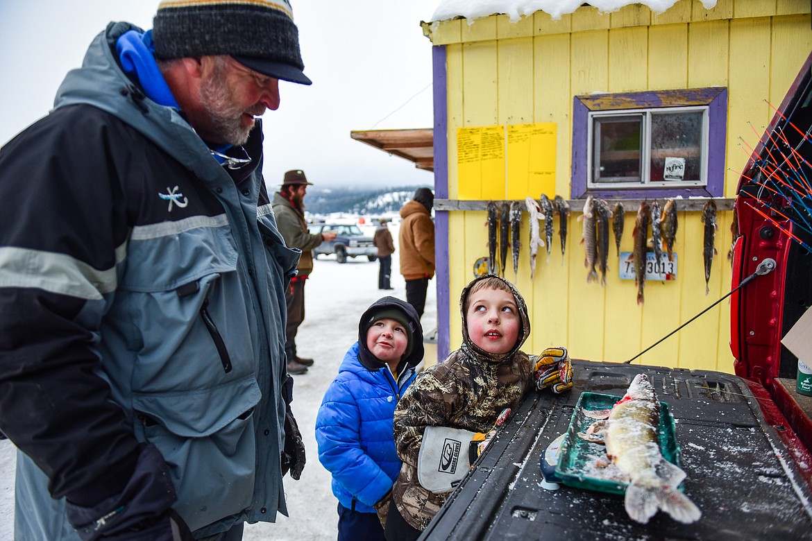 Bob Hickey, with Montana Walleyes Unlimited, weighs a pike caught by Emmett Dopps, center, and Cedar Keller at the Sunriser Lions Family Ice Fishing Derby at Smith Lake on Saturday, Jan. 7. (Casey Kreider/Daily Inter Lake)
