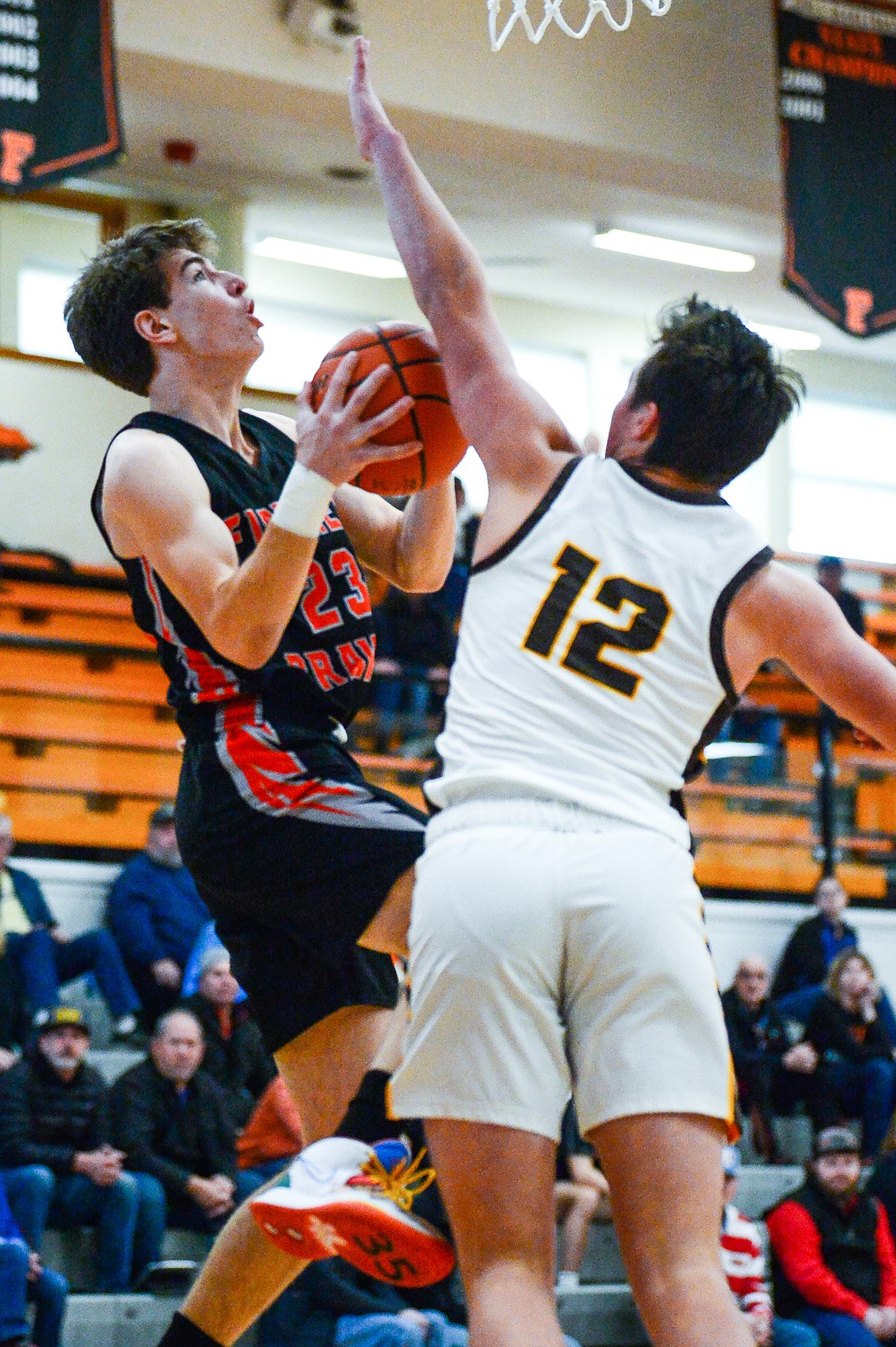 Flathead's Brody Thornsberry (23) drives into the lane and dishes to a teammate in the first quarter against Helena Capital's Hudsen Grovom (12) at Flathead High School on Saturday, Jan. 14. (Casey Kreider/Daily Inter Lake)