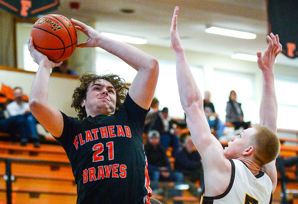 Flathead's Slate Burrington (21) knocks down a shot over Helena Capital's Nick Michelotti (5) in the first half at Flathead High School on Saturday, Jan. 14. (Casey Kreider/Daily Inter Lake)