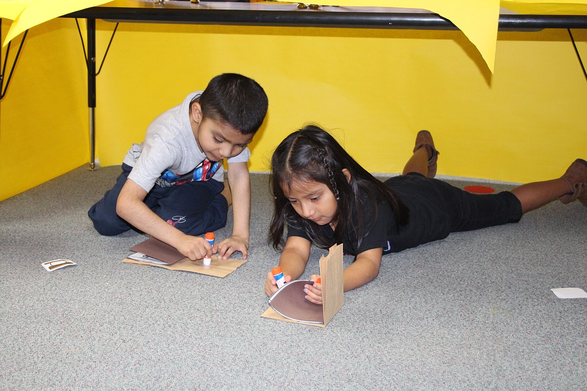 Axel Villa, left, and Briana Garcia, right, paste pictures in the books they wrote on making s’mores during Warrior Academy Friday.