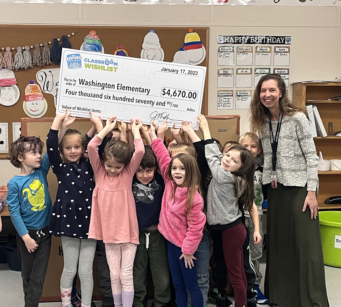 Washington Elementary kindergarten students join teacher Johanna Soderberg in holding up a sign showing the amount of a grant given by the Idaho Lottery to purchase a storage cubby system.