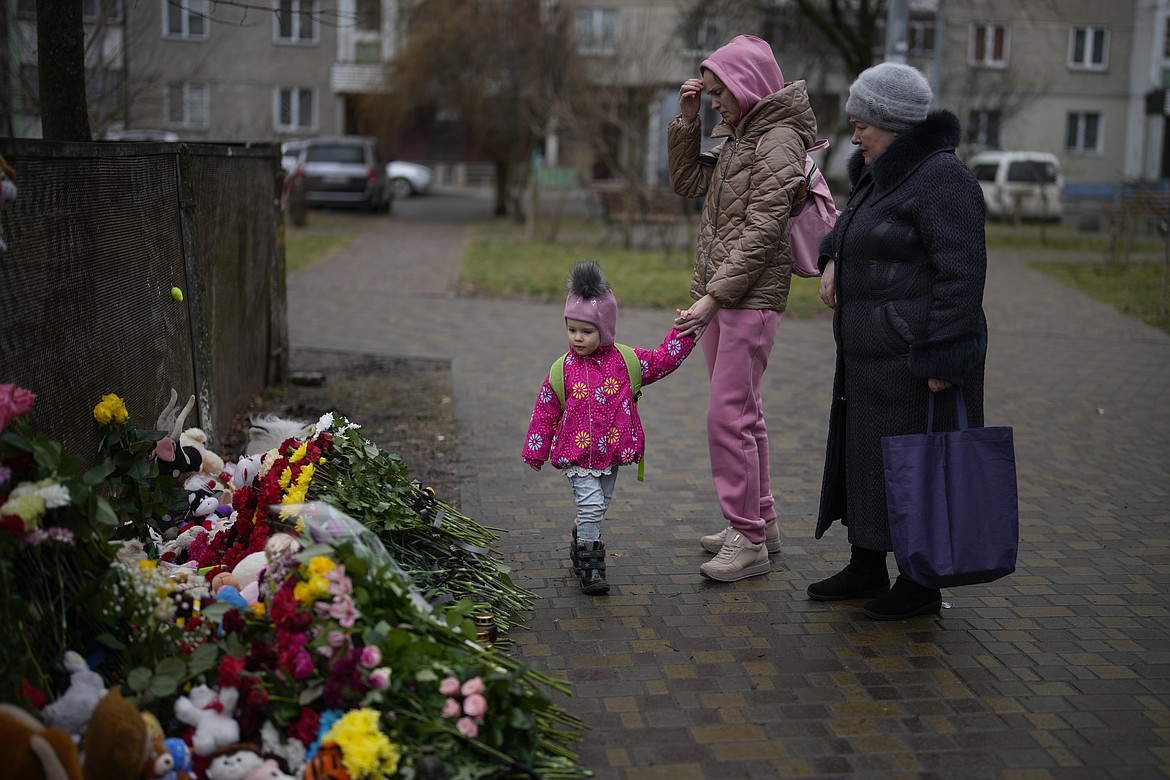 People pay their respects at the scene where a helicopter crashed into civil infrastructure on Wednesday, in Brovary, on the outskirts of Kyiv, Ukraine, Friday, Jan. 20, 2023. (AP Photo/Daniel Cole)