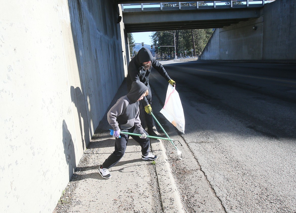 Father and son Russ and Jaxon Giles work together Saturday morning to pick up a piece of trash under the Interstate 90 overpass on East Sherman Avenue.