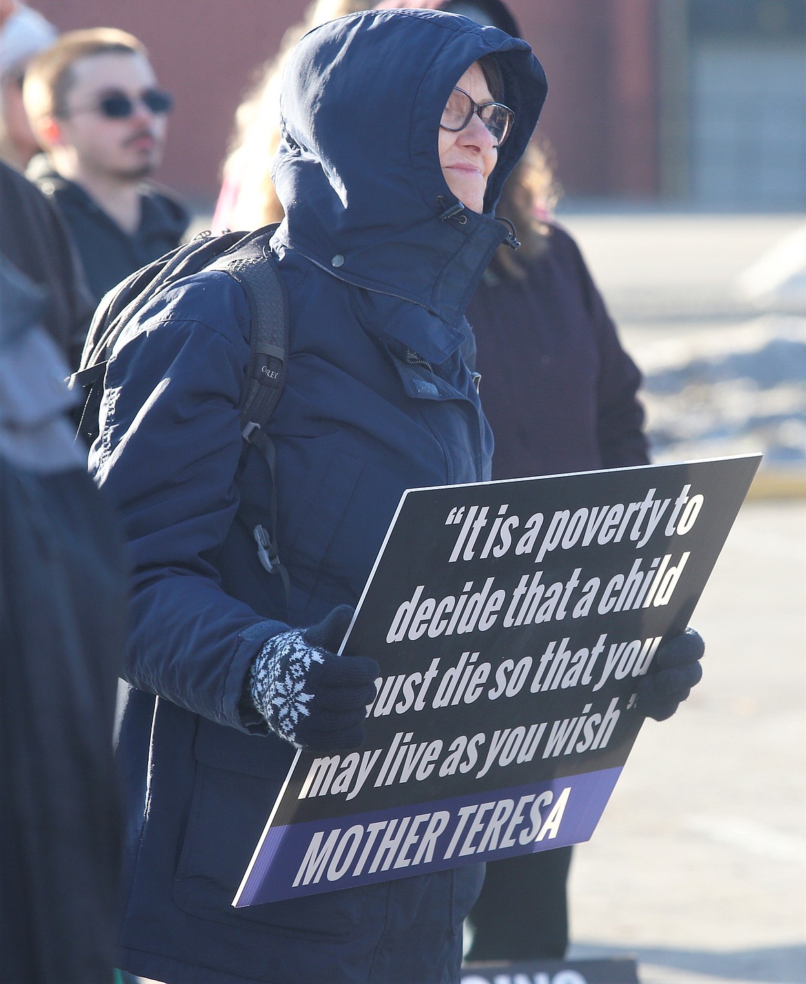 Mary Pat Lyons holds a sign as she listens to a speaker at the annual Right to Life Coeur d'Alene March and Rally on Saturday.