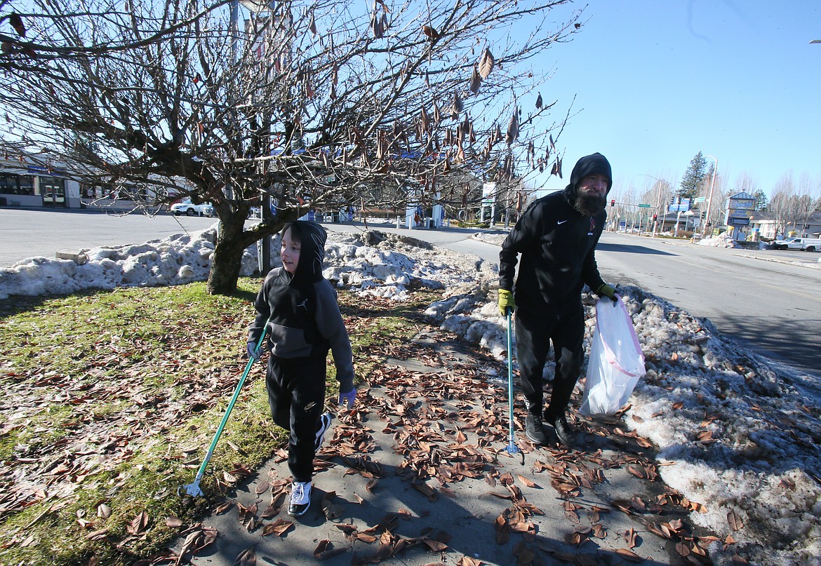 Jaxon Giles and his dad, Russ Giles, scour the area for trash Saturday morning as they walk along East Sherman Avenue. Community service has been a tradition for them since Jaxon was 3.