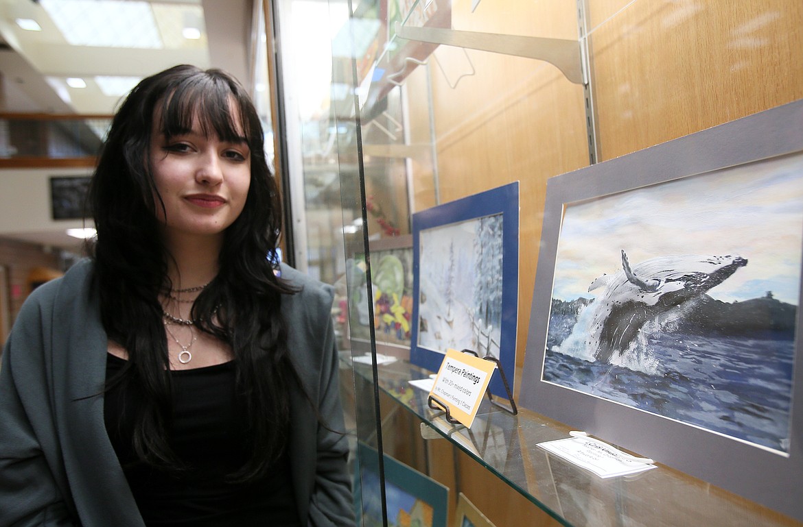 Lake City High School senior Jos Benak on Monday stands next to her tempera painting of a breaching whale on display in a hallway outside the school library. The young artist received $500 from the Jack Bannon Memorial Scholarship Fund and is in the process of planning a regional art show.