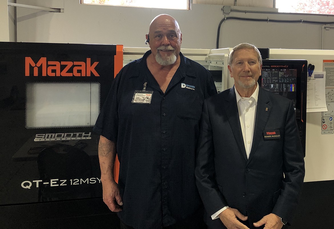 From left, Dave Fisher, owner of Dependable Machine Inc., and Richard McCauley, regional sales manager for MAZAK USA, stand together for a photo  near a MAZAK lathe at an open house in December 2022, at Dependable Machine. The machine pictured is similar to one donated by MAZAK and Dependable Machine to Kootenai Technical Education Campus to train students in the automated manufacturing department on the most-current machines to meet industry standards.