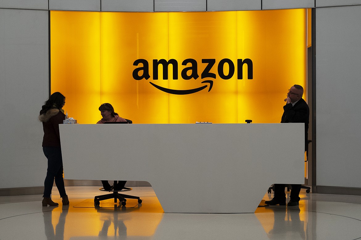 In this Feb. 14, 2019 file photo, people stand in the lobby for Amazon offices in New York. Amazon is ending a charity donation program it ran for a decade in its latest cost-cutting move. In a blog post on Wednesday, Jan. 18, 2023, the company said the program, called AmazonSmile, will shut down by February 20. (AP Photo/Mark Lennihan, File)