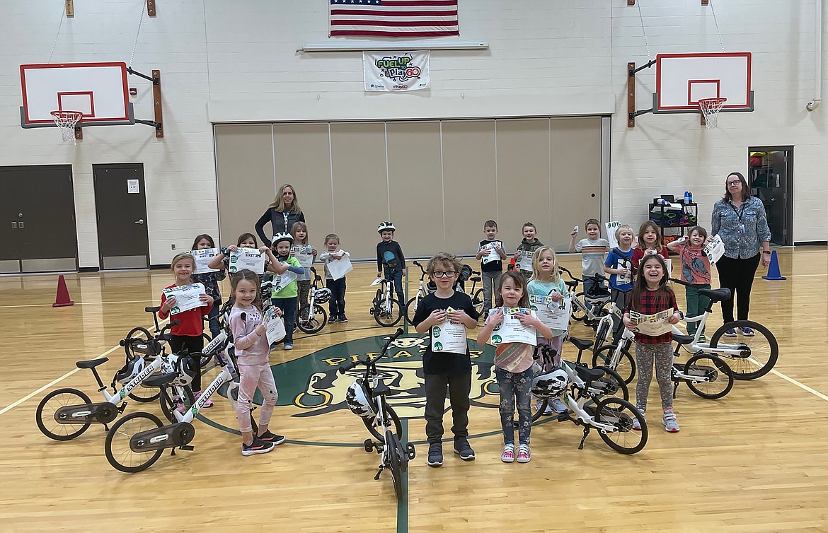 Kootenai Elementary kindergartners stand alongside new bicycles and displaying their certificates after completing a program aimed at teaching them how to ride a bicycle in a safe manner.
