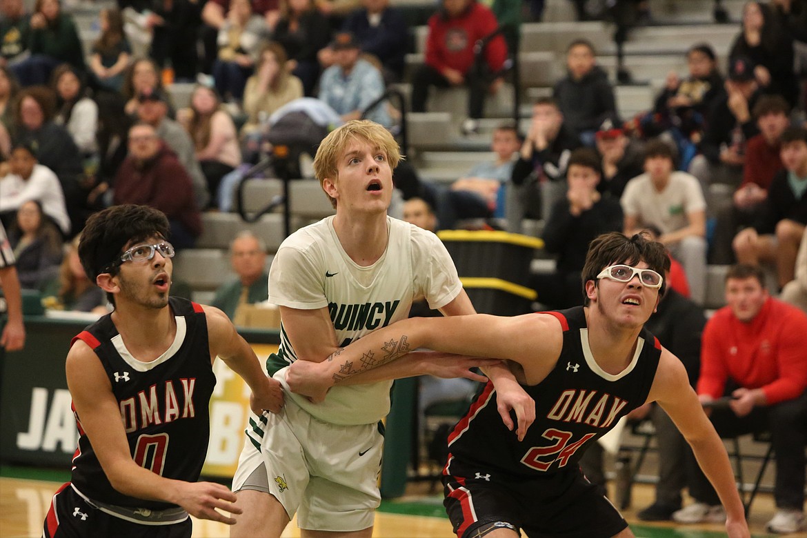 During a free throw attempt, Quincy junior Aidan Bews looks to get a rebound against two Omak players.