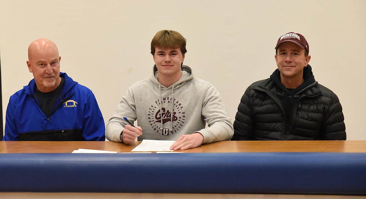 Libby Loggers football player Cy Stevenson signs his letter of intent on Monday, Jan. 30, to play with the University of Montana Grizzlies. Stevenson was joined by his father, Jeff Stevenson, and Loggers coach Neil Fuller. (Scott Shindledecker/The Western News)