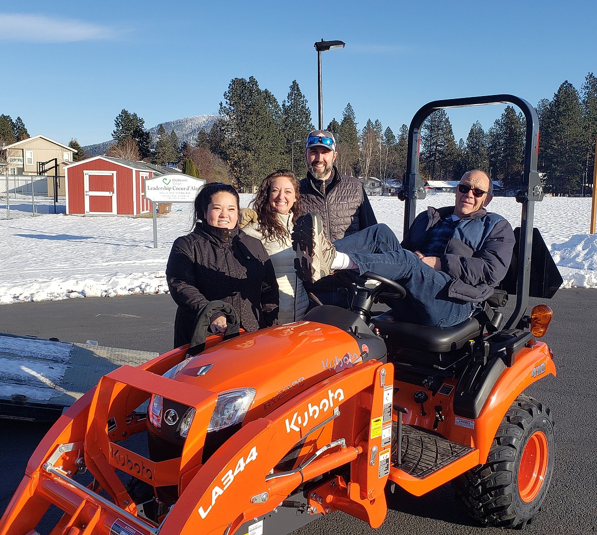 From left, Children's Village development manager Emily Aizawa and CEO Vanessa Moos; Coeur d'Alene Tractor general manager Matt Adams; and Children's Village maintenance man Duane Friesen on Monday pose with an equipment donation to the Children's Village from Coeur d'Alene Tractor. The tractor will allow Friesen and Moos to reduce operating costs for Children's Village so those funds can be focused on the children.