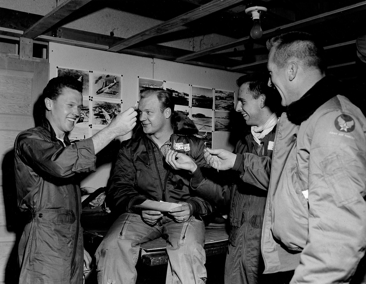 A group of airmen and pilots in a photo from 1950 appear to be having a contest to see how long each can hold a lit match in a barracks at Larson Air Force Base.