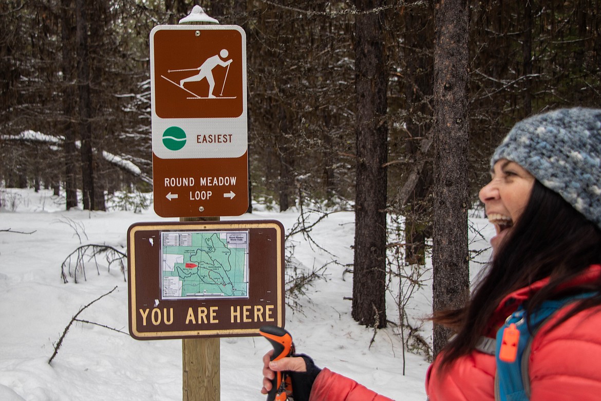 Laurie McCargar, the leader of Outsiety, laughs in front of a trail sign on Jan. 25, 2023 while cross country skiing at Round Meadow Trails. (Kate Heston/Daily Inter Lake)