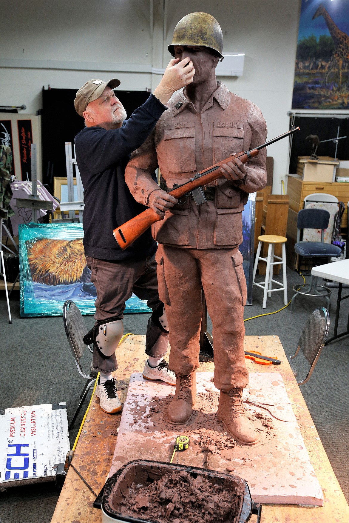 Terry Lee smooths out the nose of the statue, “US Army Soldier,” at his Hayden studio on Friday.
