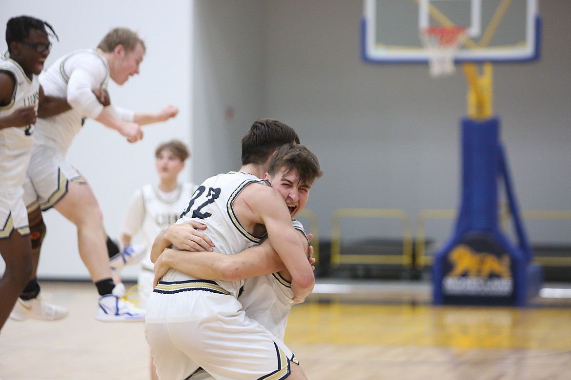 MLCA/CCS senior Michael Podolyan, center right, hugs teammate Dennis Gulenko, center left, after the Lions defeated Entiat 62-60 on their new home floor on Friday night. The win gave the Lions the Central Washington 1B title.