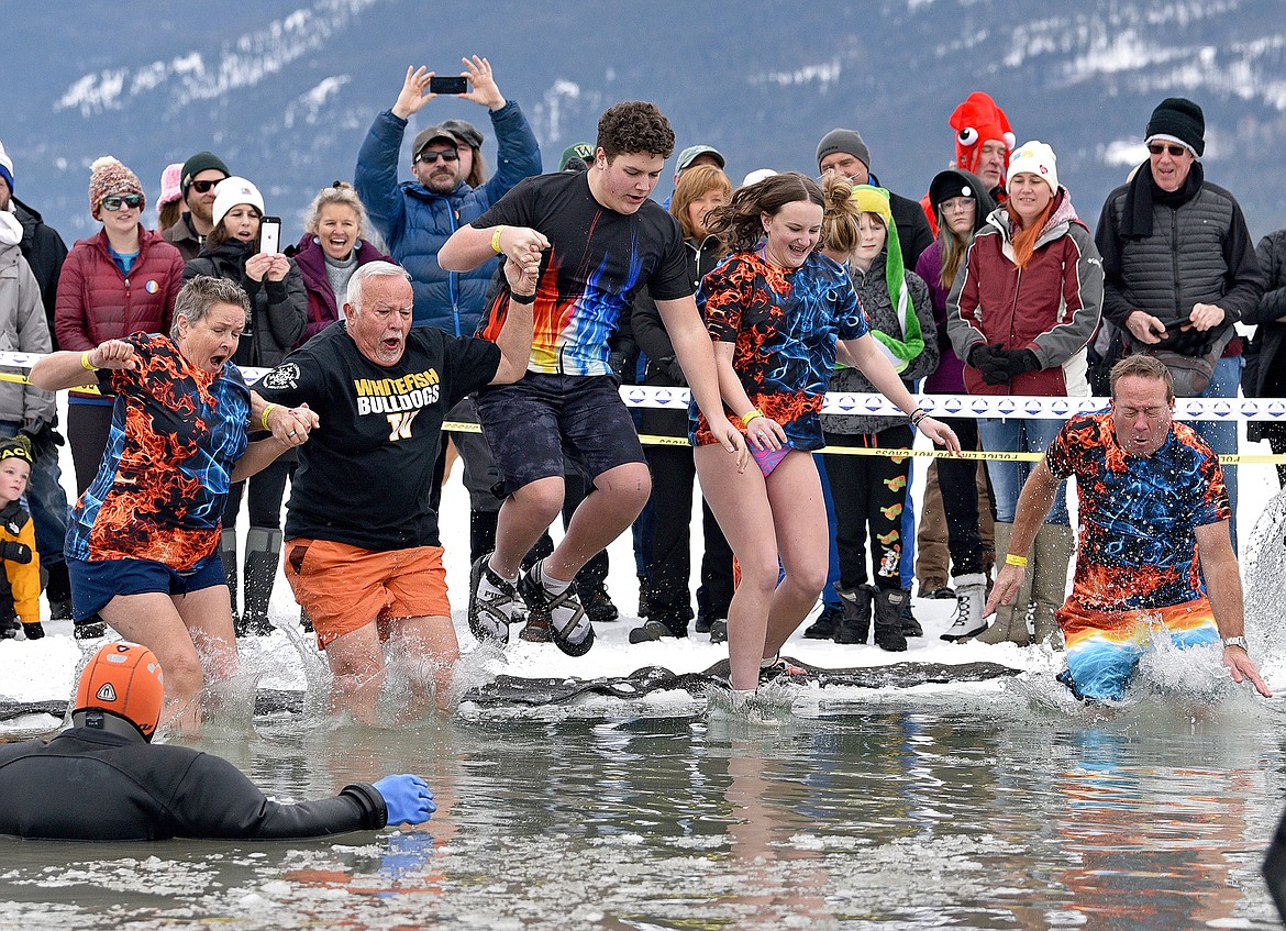 The Whitefish Winter Carnival LXIV royalty jumps into the icy cold water at the Penguin Plunge on Saturday at City Beach. (Whitney England/Whitefish Pilot)