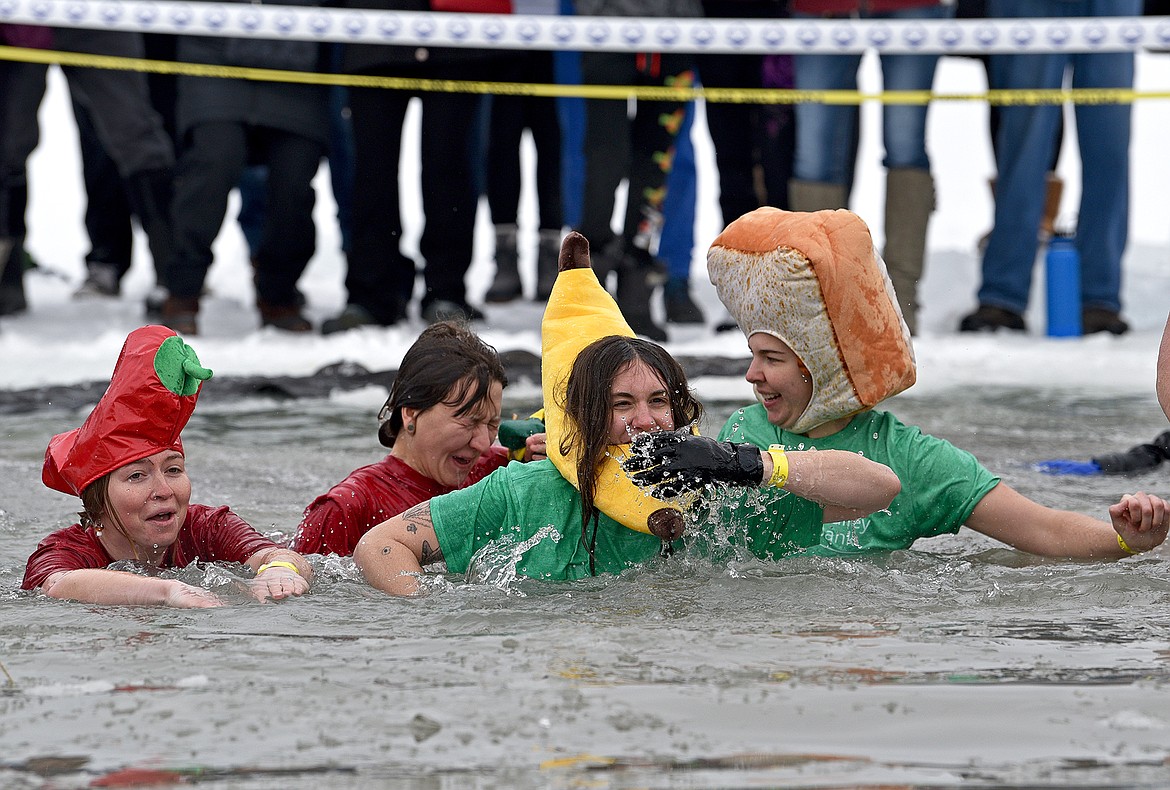 Jumpers from the NVFB embrace the cold water at the Penguin Plunge on Saturday at City Beach. (Whitney England/Whitefish Pilot)