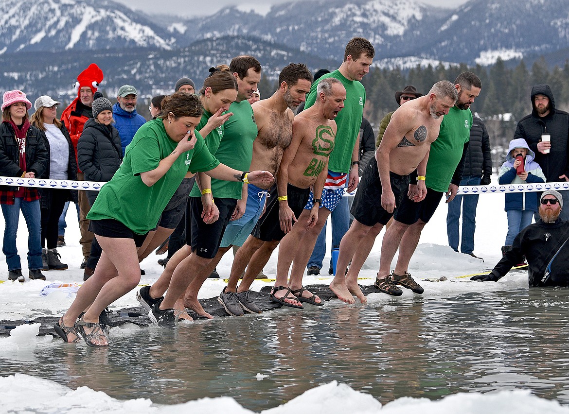 A group from Stockman Bank yells "Chop, chop, timber!" as they fall into the icy cold water at the Penguin Plunge on Saturday at City Beach. (Whitney England/Whitefish Pilot)