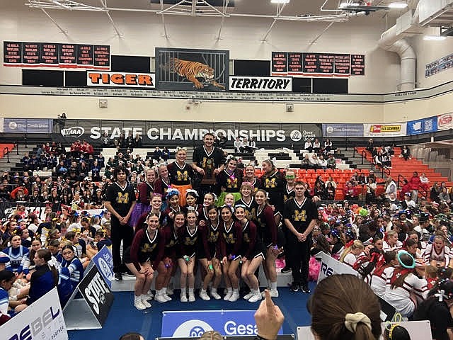 Members of the Moses Lake High School cheerleading team smile on the podium after finishing first in the 3A/4A Tumbling Coed competition on Friday.