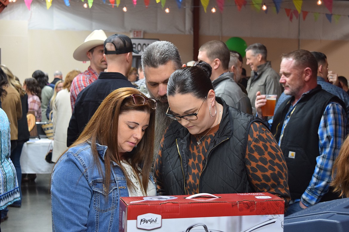 Attendees examine a silent auction item made up of cookware at the Country Sweethearts event on Feb. 4.