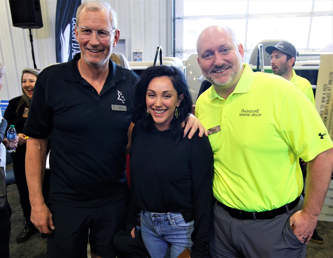 Katie Scardina is congratulated by Hagadone Marine Group President Craig Brosenne, left, and Ryan Holmes, HMG general manager, after winning a pontoon boat at the Hagadone Marine Center on Saturday.