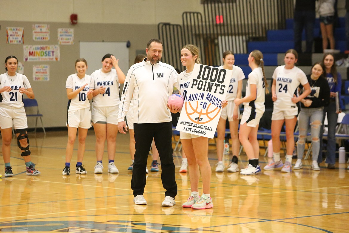 Warden Head Coach Josh Madsen, left, and junior Lauryn Madsen, right, celebrate at the center of the court after Lauryn Madsen scored her 1,000th career point.