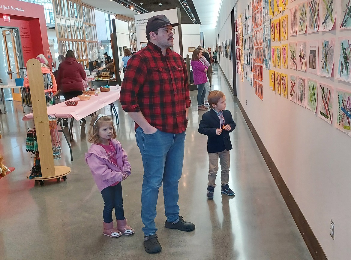 Four-year-old artist Ella Wistisen, left, looks at her work with her dad Clay Wistisen and her brother Thayne Wistisen, 6. Ella is one of more than 250 preschool students whose work is on display at the Moses Lake Museum & Art Center.