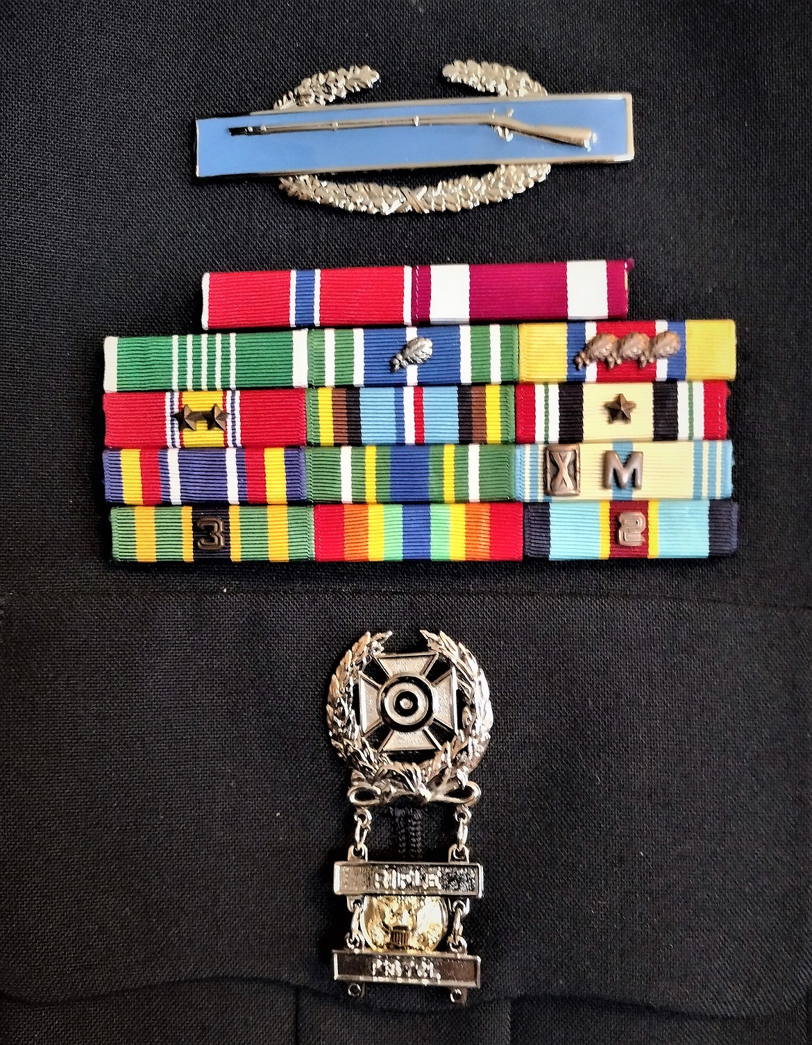 A ribbon rack adorns Jack Evensizer's uniform showing two awards of the NDSM (red and gold ribbon with two service stars) in the middle row, left side.