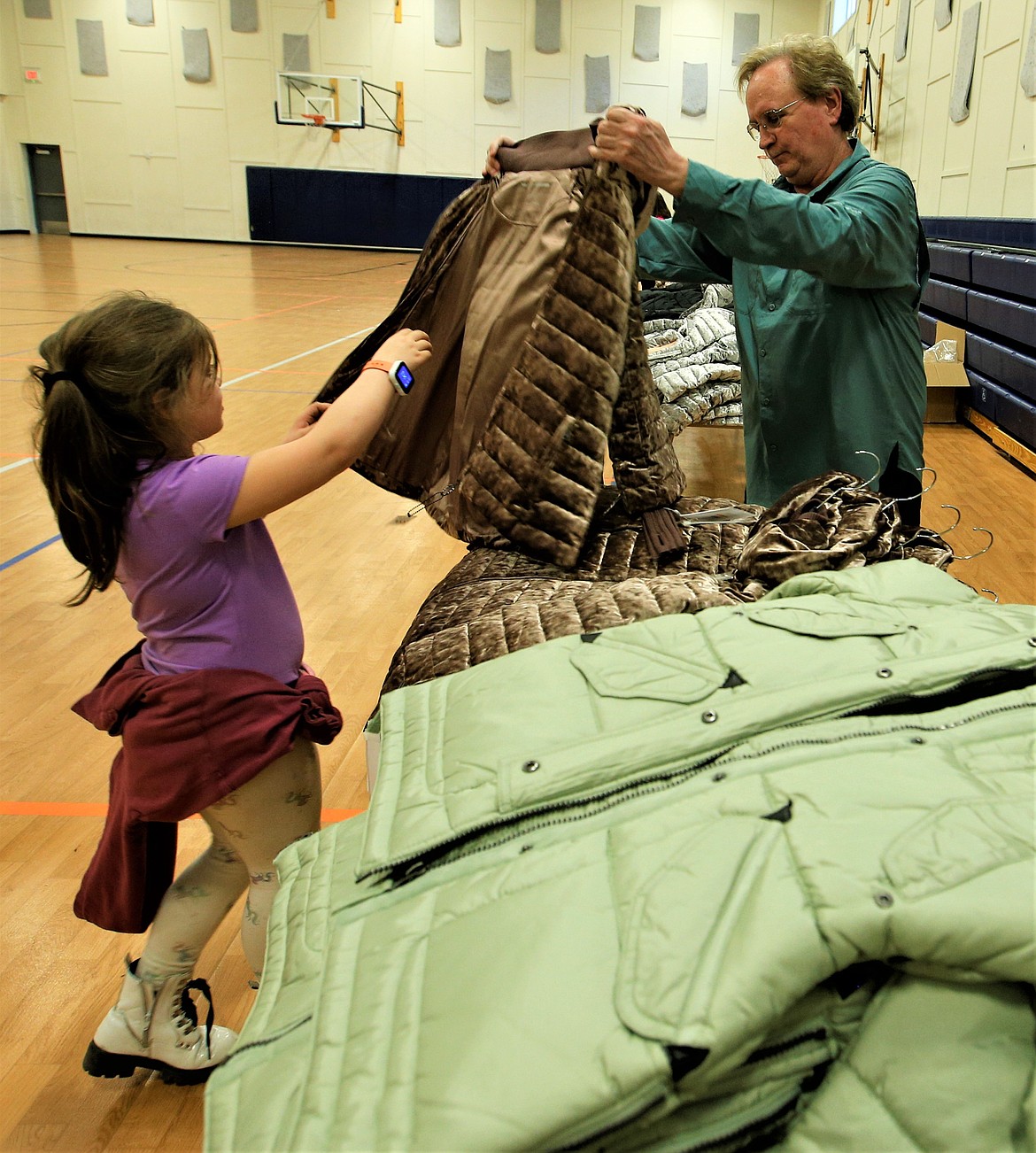 Volunteer Roger Scarlett helps a girl select a coat at the Boys and Girls Club on Thursday.