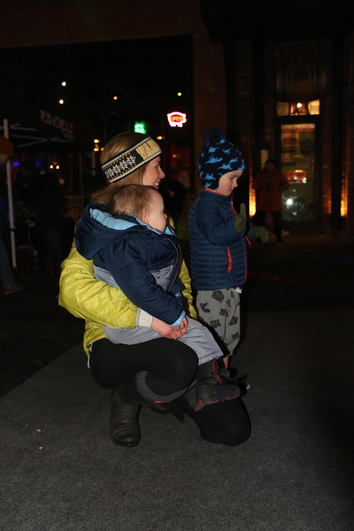 Britta Wehrle, Johannes Keaton, 3, and Clayton Lowther, 1, watch the dancers at the Winter Carnival block party in downtown Sandpoint on Friday night. The fun continues today with a packed schedule of events.