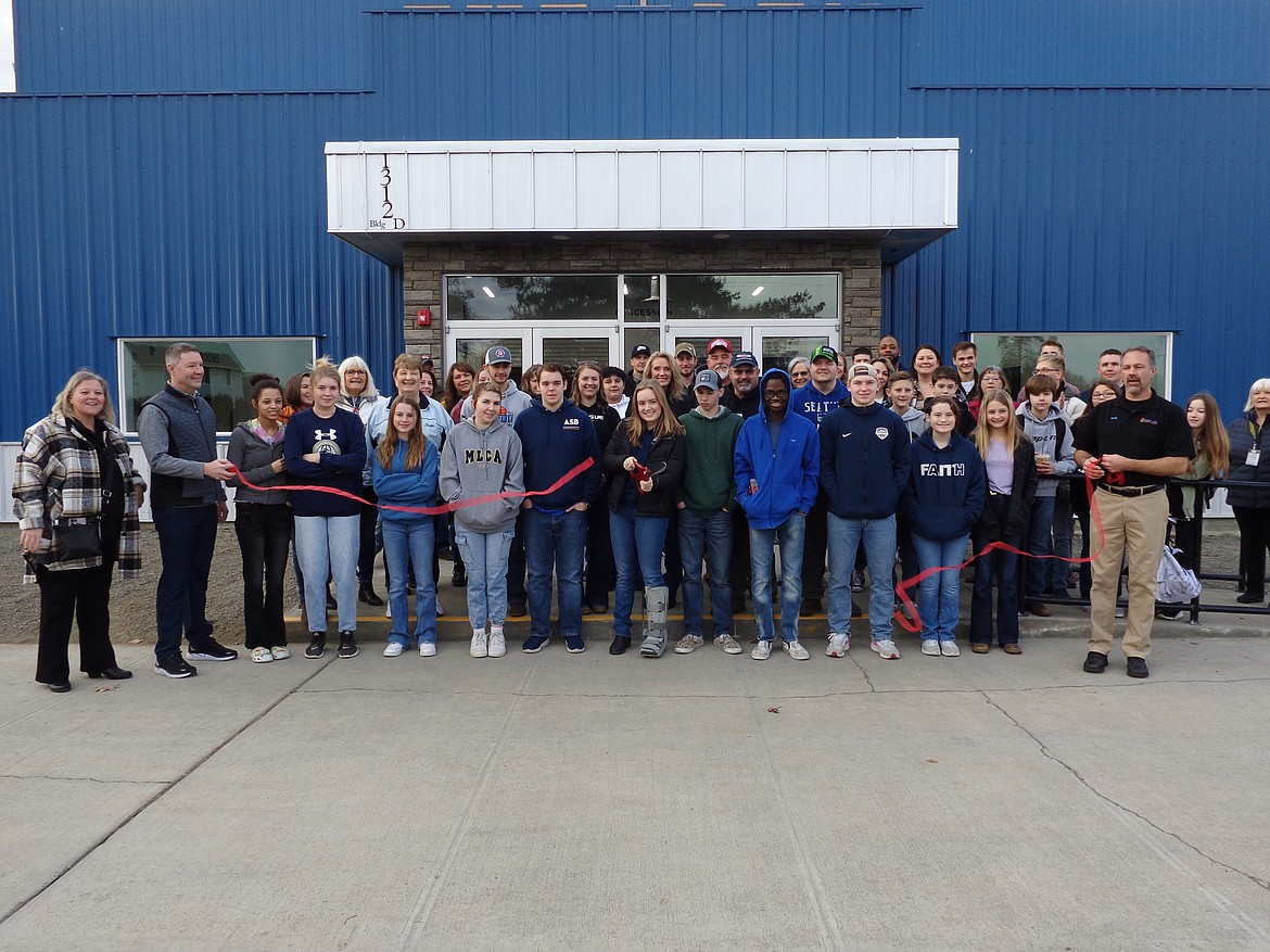 Moses Lake Christian Academy senior and 2022-23 Associated Student Body President McKenna Meise cuts the ribbon on the school’s new gym, The Den, in a short ceremony Friday morning surrounded by MLCA staff, other students and members of the Moses Lake Chamber of Commerce.