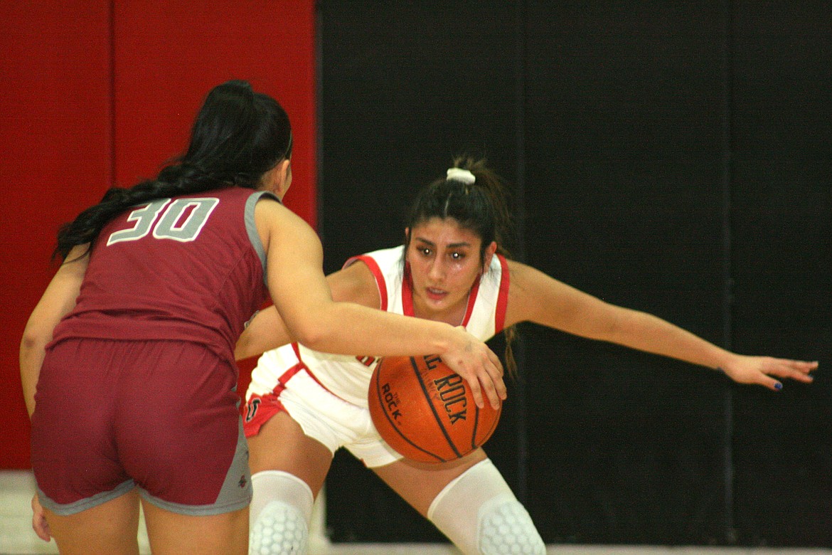 Othello’s Annalee Coronado, in white, keeps an eye on Grandview’s Jazmine Richey (30) during Othello’s 48-43 win over Grandview Thursday.