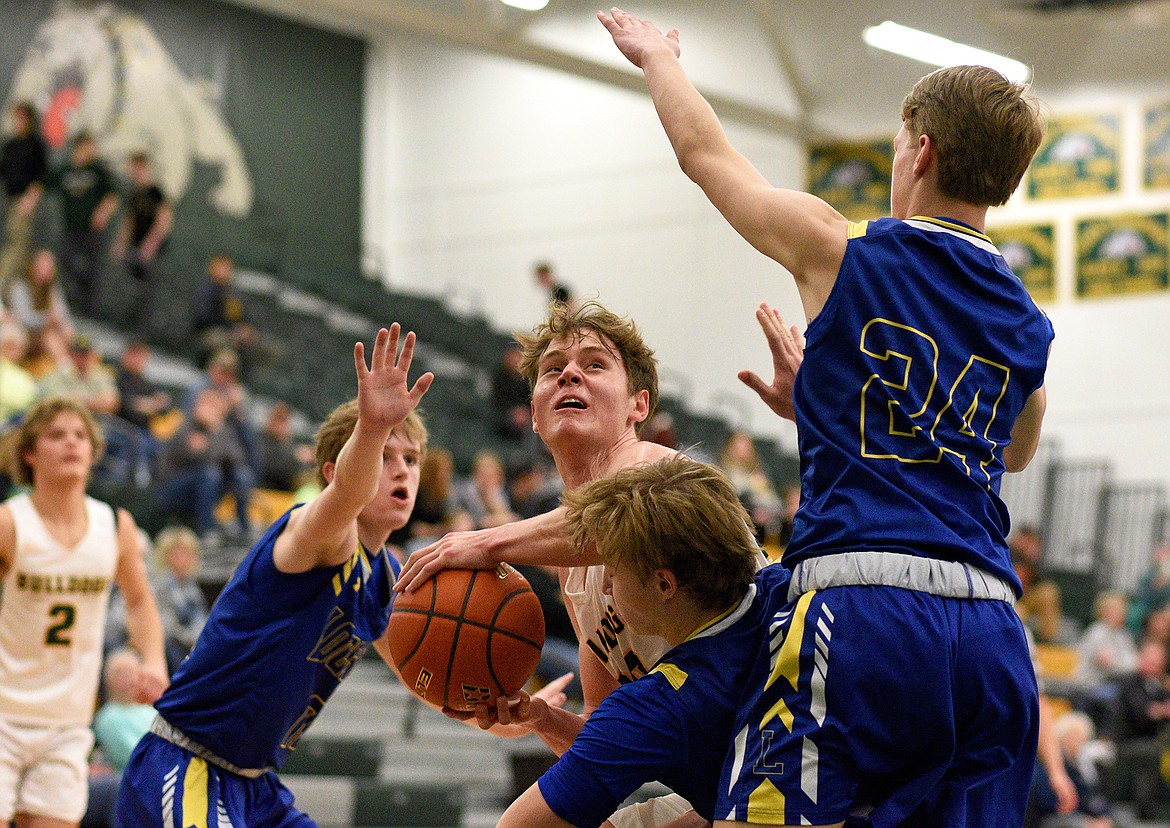 Bulldog senior Jack Sears gets clobbered by Libby on his way to the hoop on Saturday in Whitefish. (Whitney England/Whitefish Pilot)