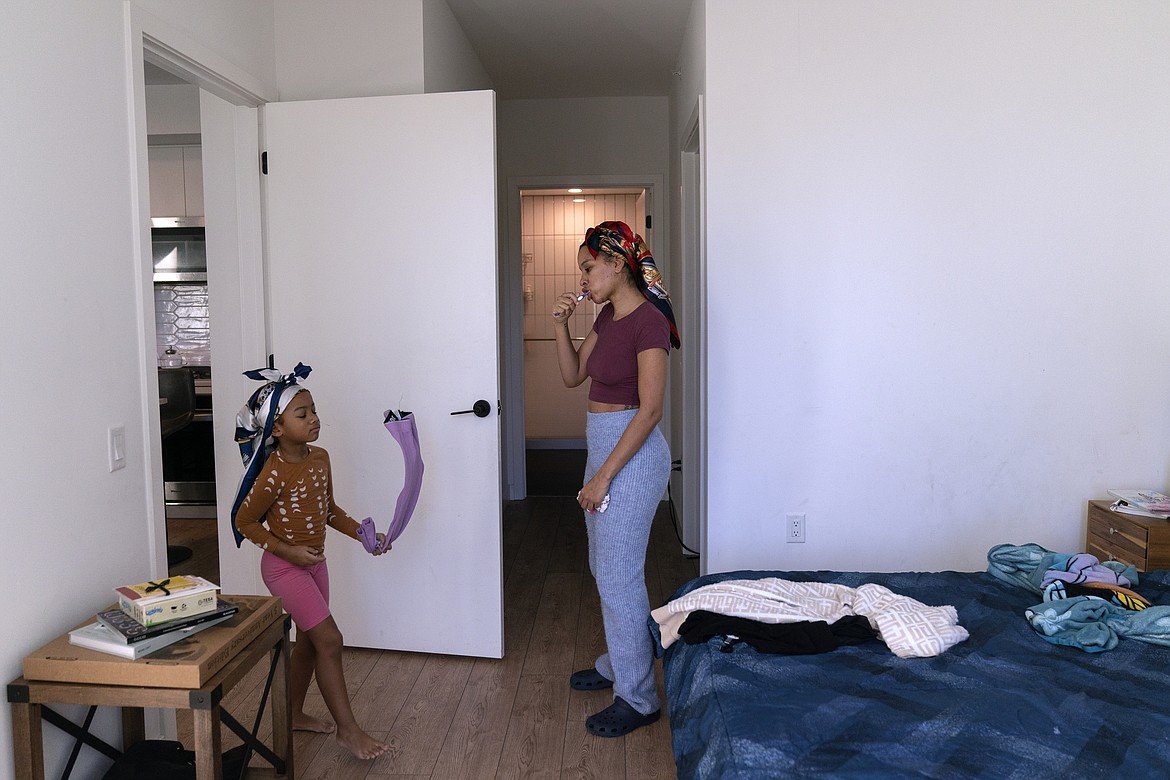 Johnae Strong brushes her teeth as she prepres her 10-year-old son and 6-year-old daughter Jari Akim, left, for school and work Friday, Feb. 10, 2023, in Chicago. (AP Photo/Erin Hooley)