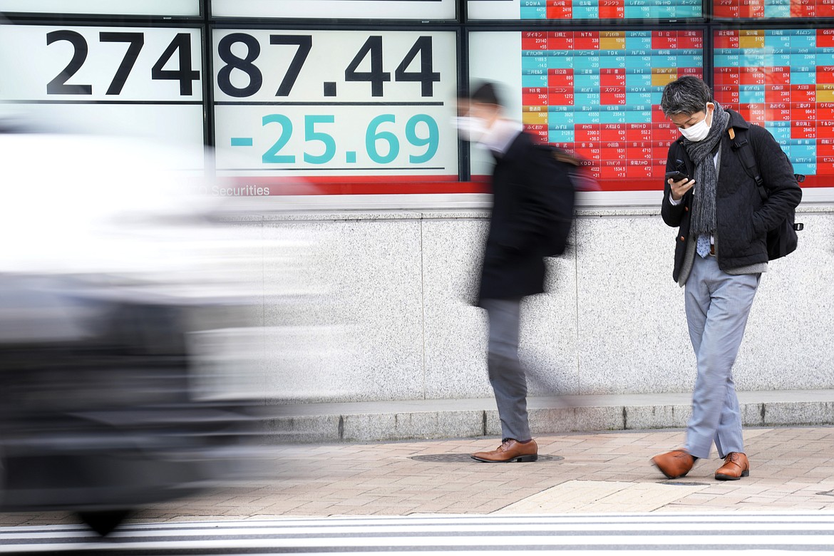 A person wearing a protective mask stands in front of an electronic stock board showing Japan's Nikkei 225 index at a securities firm Monday, Feb. 20, 2023, in Tokyo. Shares were mostly higher in Asia on Monday after Wall Street closed out another bumpy week with a mixed performance. (AP Photo/Eugene Hoshiko)