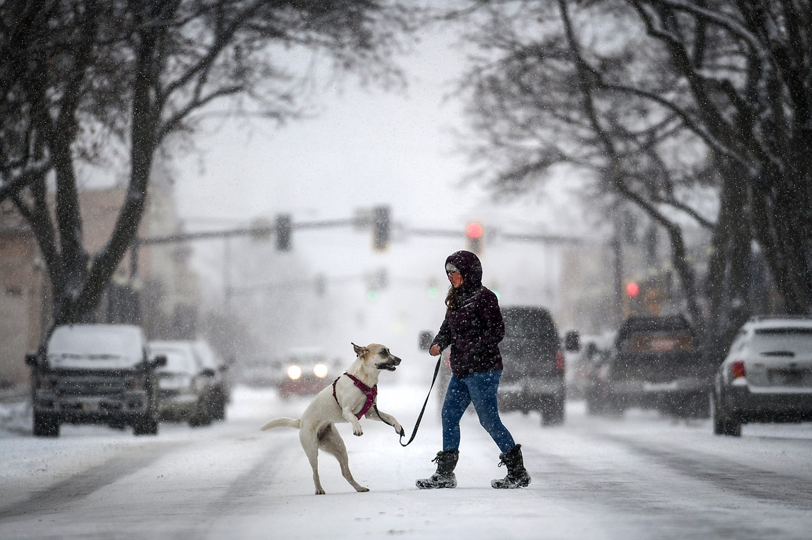 Macy Garwood and her dog Lucy cross over First Avenue West as they go for a walk in the snow on Tuesday, Feb. 21. (Casey Kreider/Daily Inter Lake)