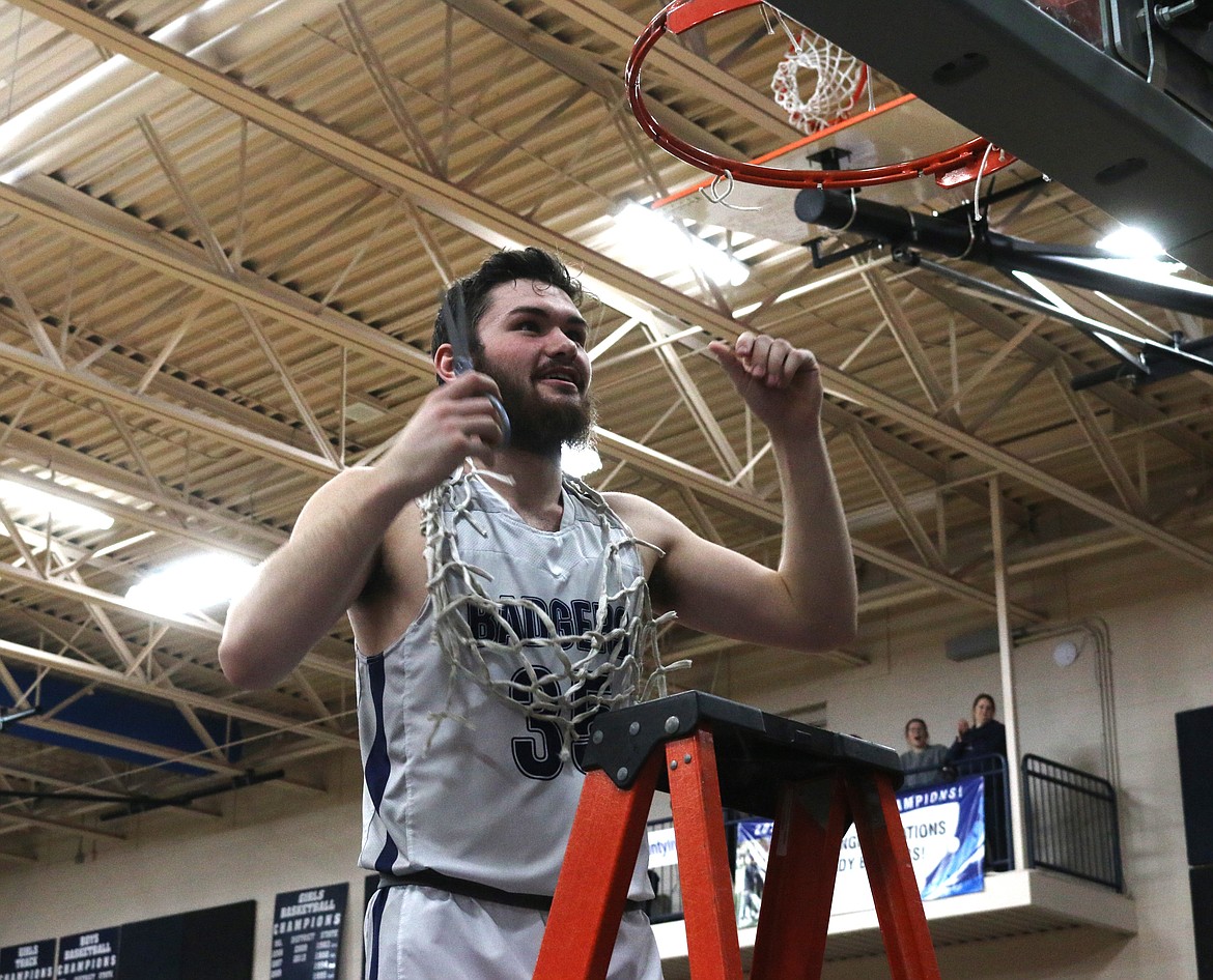 Senior Braeden Blackmore cuts the net from the district basketball game hoop.