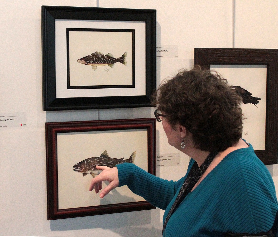 Dollie Boyd, director of the Moses Lake Museum & Art Center, points out the feather subtly incorporated in “Spotting a Lake Trout,” one of the pieces currently on display at the museum.