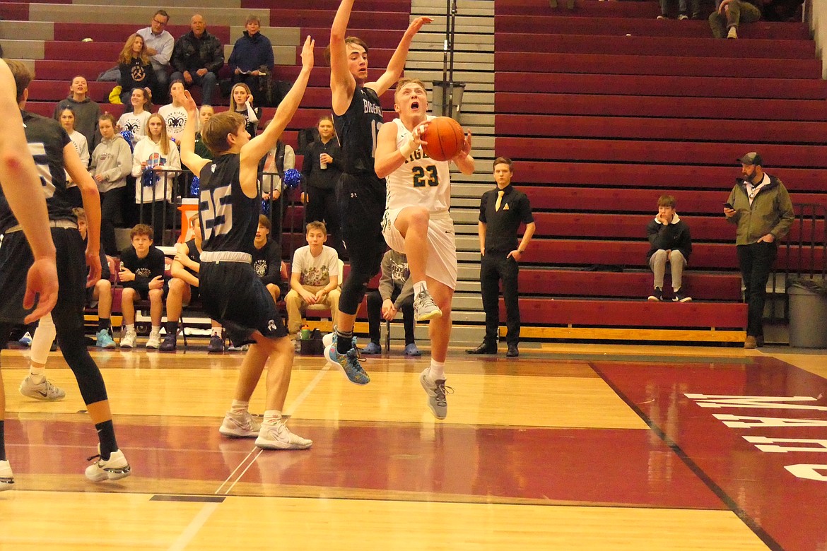 St. Regis junior John Pruitt takes the ball to the basket while being defended by Lone Peak players Max Romney (13) and Ebe Grabow (25) during first round action at the Western C Divisional tournament in Butte this past weekend. (Chuck Bandel/MI-VP)