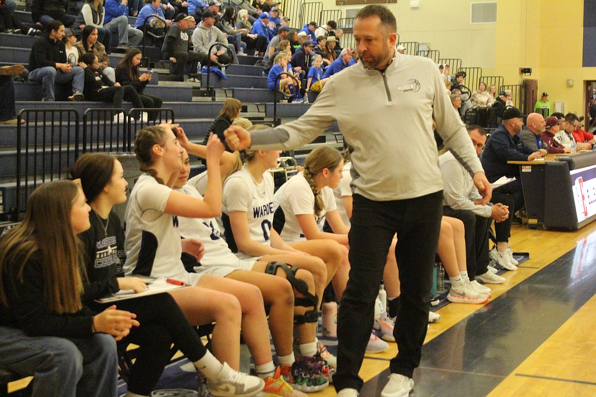 Warden Coach Josh Madsen, right, exchanges a fist bump with Quinn Erdmann during the closing moments of Saturday’s first-round state playoff game, a Warden win.