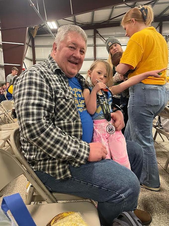 Peewee wrestler Everly Graham enjoys herself with grandpa Jay Graham, a long-time Libby High School wrestling team coach, at the Maverick Bench Memorial Tournament Saturday, Feb. 25, in Kalispell. (Photo courtesy Libby Wrestling Club)