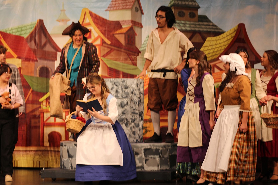 Belle (Hailey Beegle), center, reads on, unconscious of the curiosity of the villagers.